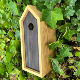 vogelhuisje met zwart en goud gekleurd hout in bossage