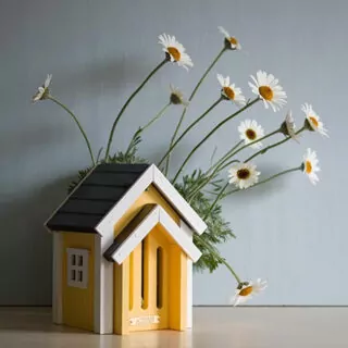 Geel huisje voor vlinders op tafel met madeliefjes